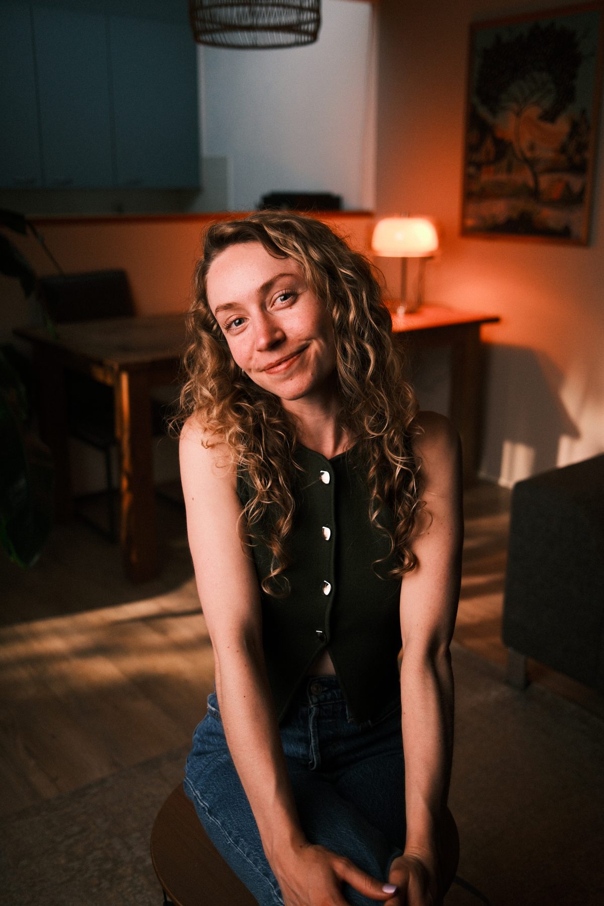 Sarah Koedam, zittend in een woonkamer bij lamplicht